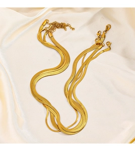 Close-up of 18K gold-plated stainless steel snake bone chains on champagne silk fabric