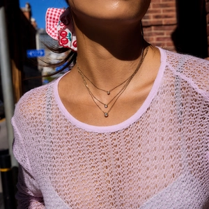 Detailed view of triple-layered gold necklace with zircon pendants on neck