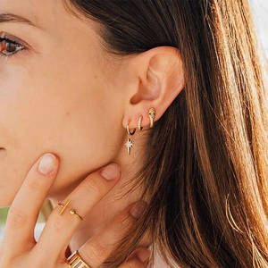 Detailed view of gold star dangle earrings and snake ear cuff on a fashion model