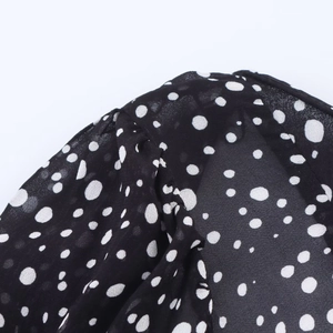 Detailed macro view of black chiffon fabric featuring classic white polka dot patterns