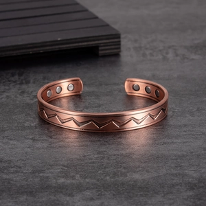 Adjustable magnetic copper bracelet with zigzag pattern on a textured background