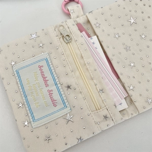 Detail of off-white canvas wallet with star rivets, card slots and pink hook attachment