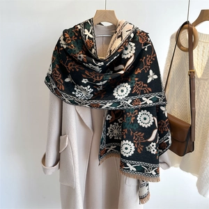Detail of floral cashmere-like scarf with tassels on beige coat background