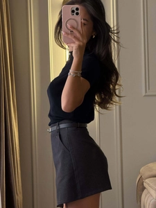 Side view of a slim-fit black short-sleeve Polo shirt and high-waisted grey shorts