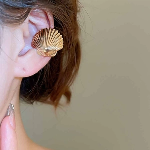 Detail of rose gold shell ear cuff showing smooth metallic ridges and radiant texture