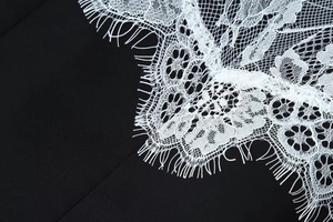 Détail de dentelle blanche sur le tissu noir d'une robe élégante à col en V