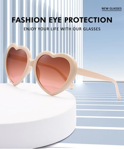Close-up of pink oversized heart sunglasses with gradient lenses on a geometric display