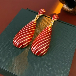 Détail de boucles d'oreilles vintage en émail rouge et rayures dorées sur écrin bijoux