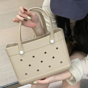 Detail view of beige EVA beach bag featuring signature round holes and white buckles