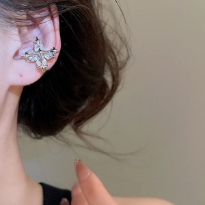 Close-up of a silver bow earring cuff with white zircon stones worn on the ear
