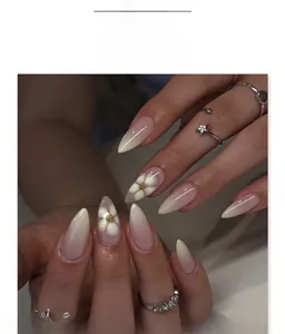 Detail of almond-shaped press-on nails with white flower design and gold beads, model JP3943