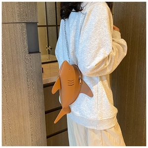Brown shark-shaped leather crossbody bag with chain strap shown on a model