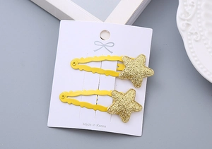 Close-up of cute glittery yellow star hair clips for girls on a white display card