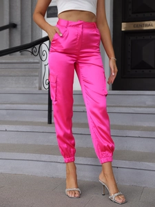 Detail of bright pink satin cargo pants with multi-pocket design and elastic cuffs for women