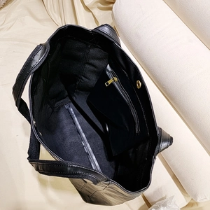 Détail intérieur du grand cabas noir montrant la poche zippée et le bouton pression doré