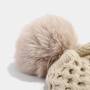 Detailed macro view of khaki knitted hat with fluffy faux fur pompom and diamond pattern