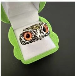 Detailed close-up of a vintage owl ring with orange eyes in a green jewelry box