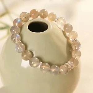 Natural labradorite beaded bracelet with ornate silver metal spacer beads on ceramic vase
