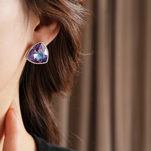 Gros plan d'une boucle d'oreille triangle avec cristal violet iridescent sur le mannequin