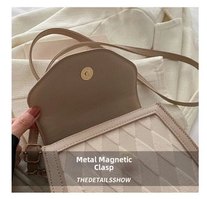 Detail of metal magnetic closure and quilted texture on beige crossbody square bag