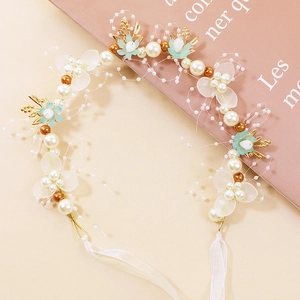 Détail de couronne fleurie avec perles, fleurs bleu clair et rubans sur fond beige doux