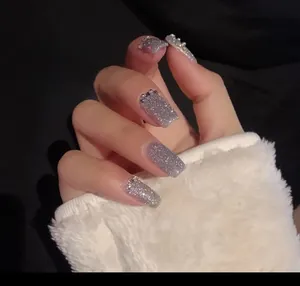 Macro shot of silver glitter nail polish with disco diamond sparkles and rhinestone accents