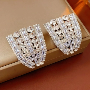 Gros plan de boucles d'oreilles en argent avec strass brillants sur coffret champagne