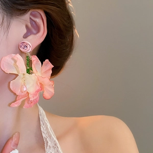 Close-up of pink fabric flower tassel earrings worn by a model in soft warm lighting