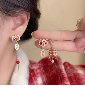Detailed close-up of festive red and gold Chinese guardian lion earrings with silk tassels