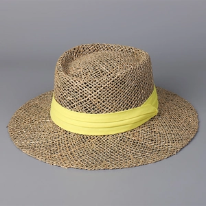 Close-up of hand-woven straw sun hat featuring a wide brim and yellow silk ribbon trim