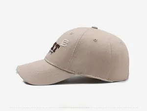 Close-up of distressed beige baseball cap featuring vintage holes and brown ET embroidery