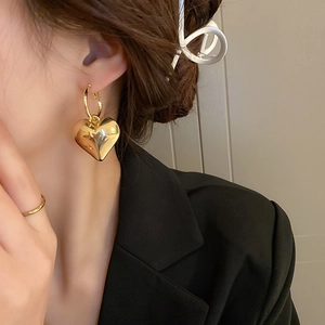 Nahaufnahme eines Models mit minimalistischen goldenen Herzohrringen mit glänzendem Spiegeleffekt