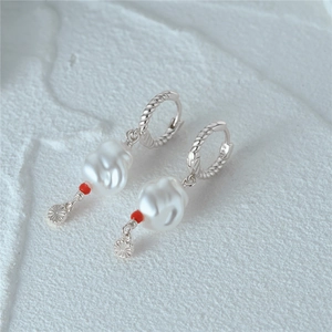 Macro shot of S925 sterling silver twist earrings featuring unique pearl and sunburst motifs