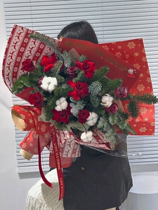 Close-up of a large Christmas bouquet with red roses, cotton, and gold-stamped paper