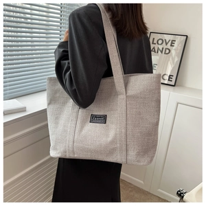 Side view of large grey canvas tote bag showing textured fabric and fashion label detail