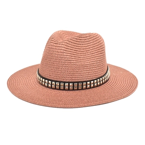 Detail of pink straw fedora featuring a black ribbon with double row golden square studs