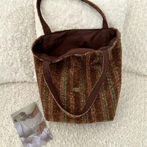 Detail view of large sherpa tote bag lining with metal logo and dark green stripe