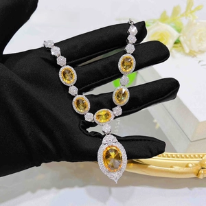 Close-up of luxury silver necklace with oval yellow gemstones and zircon pavé halo