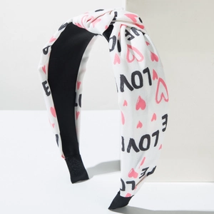 Macro detail of white knot headband with love lettering and pink heart patterns