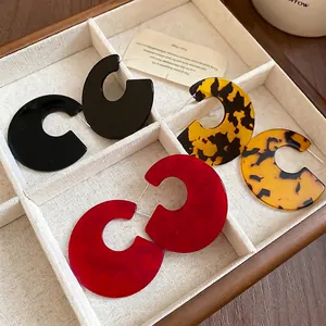 Three pairs of large C-shaped acrylic earrings in black, red marble, and tortoiseshell