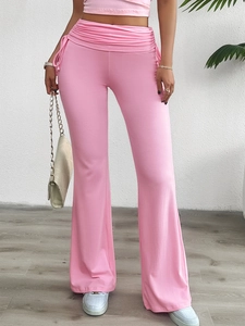 Détail du pantalon évasé rose à taille haute avec plis sur le devant et tissu doux et souple