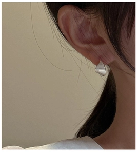 Detailed view of sterling silver shell-shaped earrings with fine vertical textures