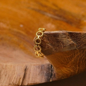 Detailed view of the gold-toned beaded chain ring hanging on a rustic wooden stand