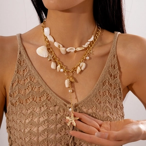 Detail of double-layer gold necklace with shell, starfish pendant and white pearl accents