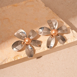 Detail view of silver metal flower earrings with champagne pearls on a stone base
