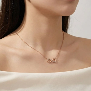 Detail of rose gold infinity necklace with zircons worn by a model in elegant style
