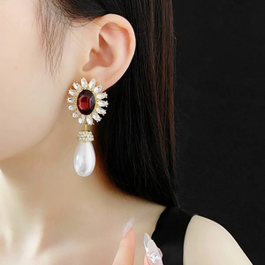 Detailed shot of floral earrings featuring ruby red gems and water-drop pearl pendants
