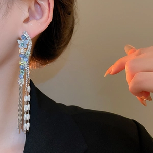 Close-up of butterfly earrings with pearls and tassels on model showing elegant detail