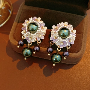 Detailed macro of vintage resin flower earrings with dark pearl tassels on brown velvet