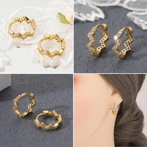 Primer plano de pendientes ondulados bañados en oro de 18K con circonitas y vista puesta